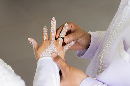 Groom hands puts wedding ring on bride