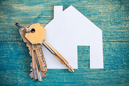 House icon and keys on wooden background