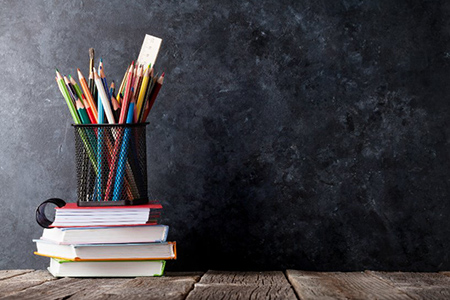 Supplies over notepads in front of chalk board. back to school concept with copy space