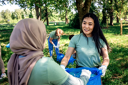 Multiethnic group of volunteers with garbage bags cleaning city park