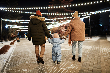 back view of a man and woman spending winter evening with their toddler kid walking