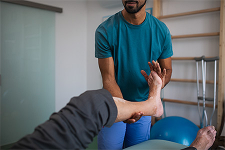 A close-up of physiotherapist exercising with senior patient's leg in a physic room