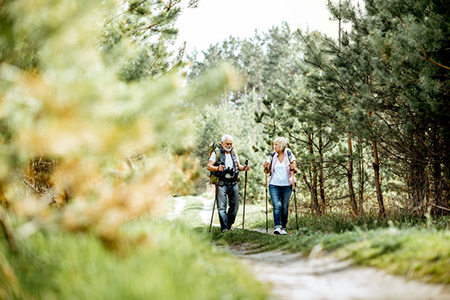 senior couple hiking with trekking sticks and backpacks