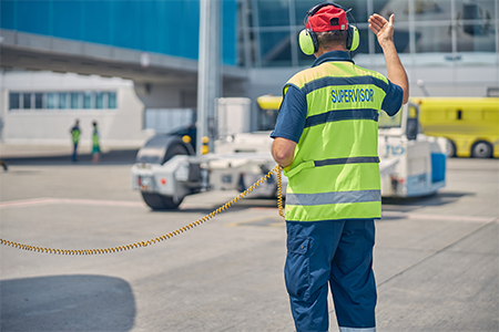 Supervisor standing in front of a pushback tug at the airport