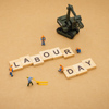 Miniature people : Worker team building word Labor day on wood background