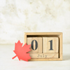 Wooden cube calendar with date JULY 1 and maple leaf on light background