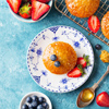 Muffin, cupcake with fresh berries on a plate. Blue background. Top view. Copy space.