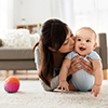 happy young mother kissing little baby at home