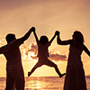 Silhouette of happy family who playing on the beach at the sunset time. Concept of friendly family.