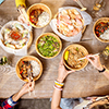 top view table full of food - people eating with chopsticks