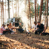 Group of friends are together in the forest by bonfire in the evening