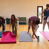 Multiracial men and women arranging exercise mats on hardwood floor in yoga studio