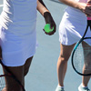 Midsection of multiracial tennis players with rackets and ball standing at court on sunny day