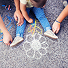 parents and baby drawing with chalk on ground