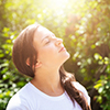 Woman smelling the fresh air outside. Background trees and sunshine