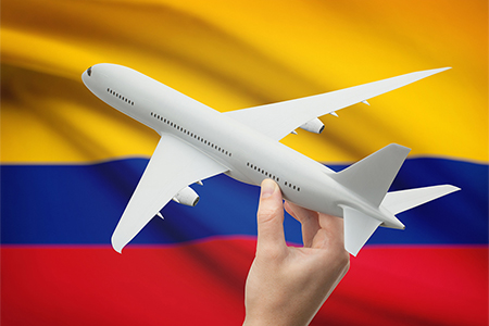 Airplane in hand with national flag on background - Colombia