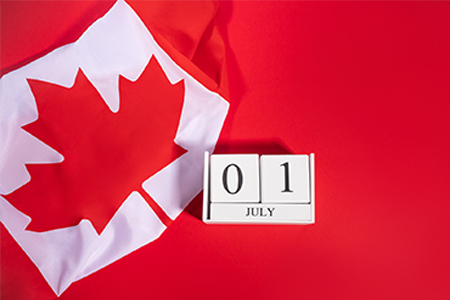 Canada Day concept with Canadian flag fragment and July 1 date on white wooden calendar
