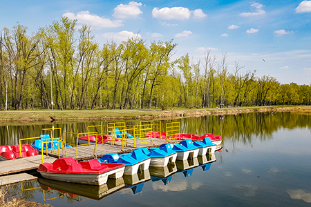 Colorful catamarans stand in a row at the wooden pier; on an early spring or summer sunny morning
