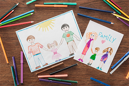 color pencils and felt pens, and white papers with drawings of family