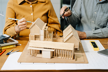 Two colleagues discussing architectural project at construction site at desk in office