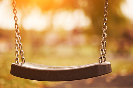 Empty children swing at sunset time closeup