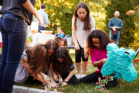 Young girls collecting sweets from a broken pi–ata