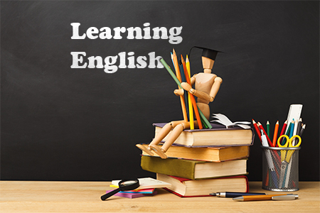 Wooden mannequin in graduation hat sitting on books pile with lots of color pencils