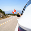 holding Canada flag from the open car window driving along the serpentine road in the mountains
