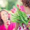 concept - Women's day; Woman and child with bouquet of flowers against green blurred background