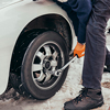 Mechanic wearing orange gloves and winter clothes, changing car wheel