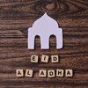 Eid Al Adha word with mosque ornament on wooden background for islamic festive celebration