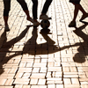 Kicking it with some friends. Cropped image of legs kicking a ball with shadows on the paved road