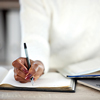 woman making notes in a book while studying