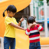 asian little girl pulling her sister's hair in the playground