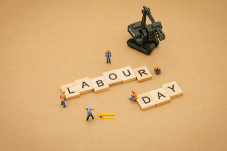 Miniature people : Worker team building word Labor day on wood background