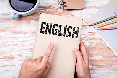 English. Hands holding book on office table.