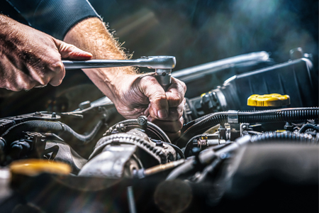 Auto mechanic working on car engine in mechanics garage. Repair service. authentic close-up shot