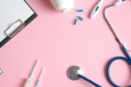 Flat lay composition with stethoscope, pills and thermometer on pink background