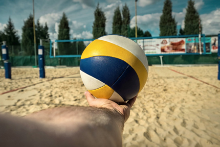 Volleyball ball in the hand of a man on the beach