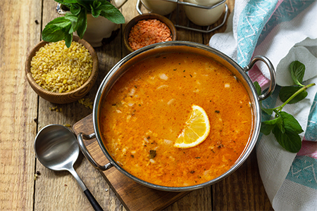 Traditional soup with rice, lentils and mint on a rustic table