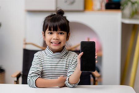 a little girl uses smartphone while sitting at the sofa in the living room