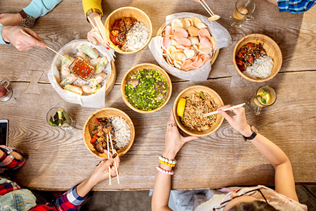 top view table full of food - people eating with chopsticks