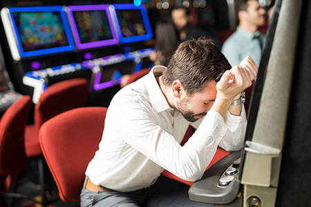  man feeling sad and stressed after losing his money playing slots in a casino