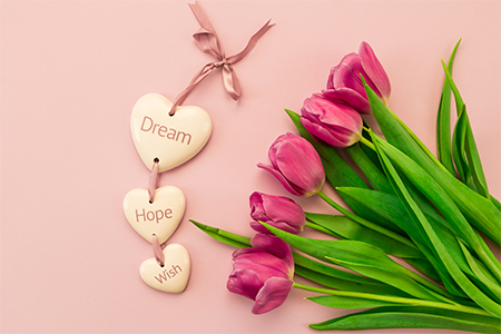 pink and purple tulips on a pink background and ceramic hearts with the inscription Dream, Hope, Wis