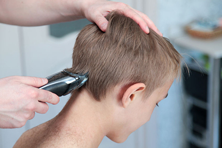 Blond boy gets haircut at home during quarantine isolation. 