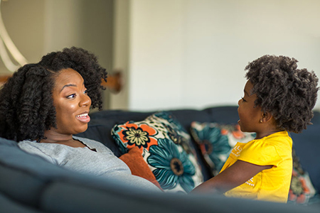 African American mother playing and talking with her daughter.