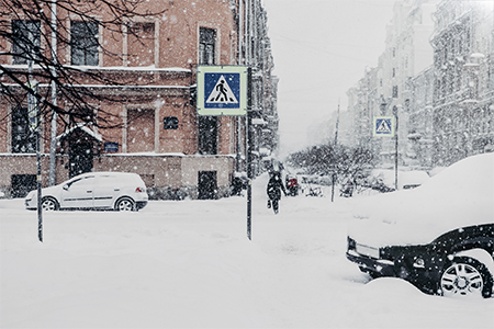 Outdoor shot of beautiful snowy city with transport and people, covered with thick white snow