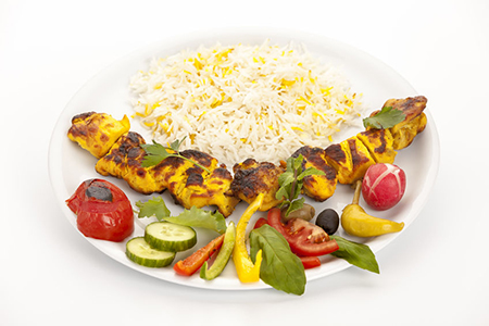 Grilled, marinated morsels of chicken without bones arranged on a plain white plate. Fusion food con