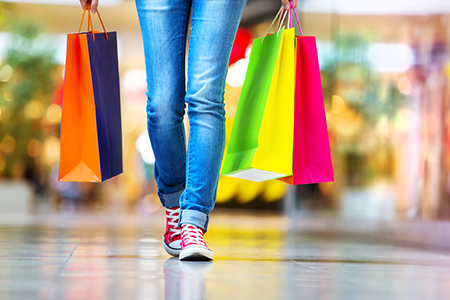 woman in mall holding shopping bags - cropped at legs