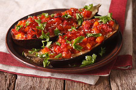 Turkish halves of baked eggplant stuffed with vegetables close-up on a plate. horizontal